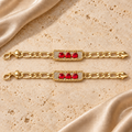 Juego de dos pulseras en tono dorado con cadena Figaro y placas de tres corazones rojos en ambas piezas, mostradas completas.
