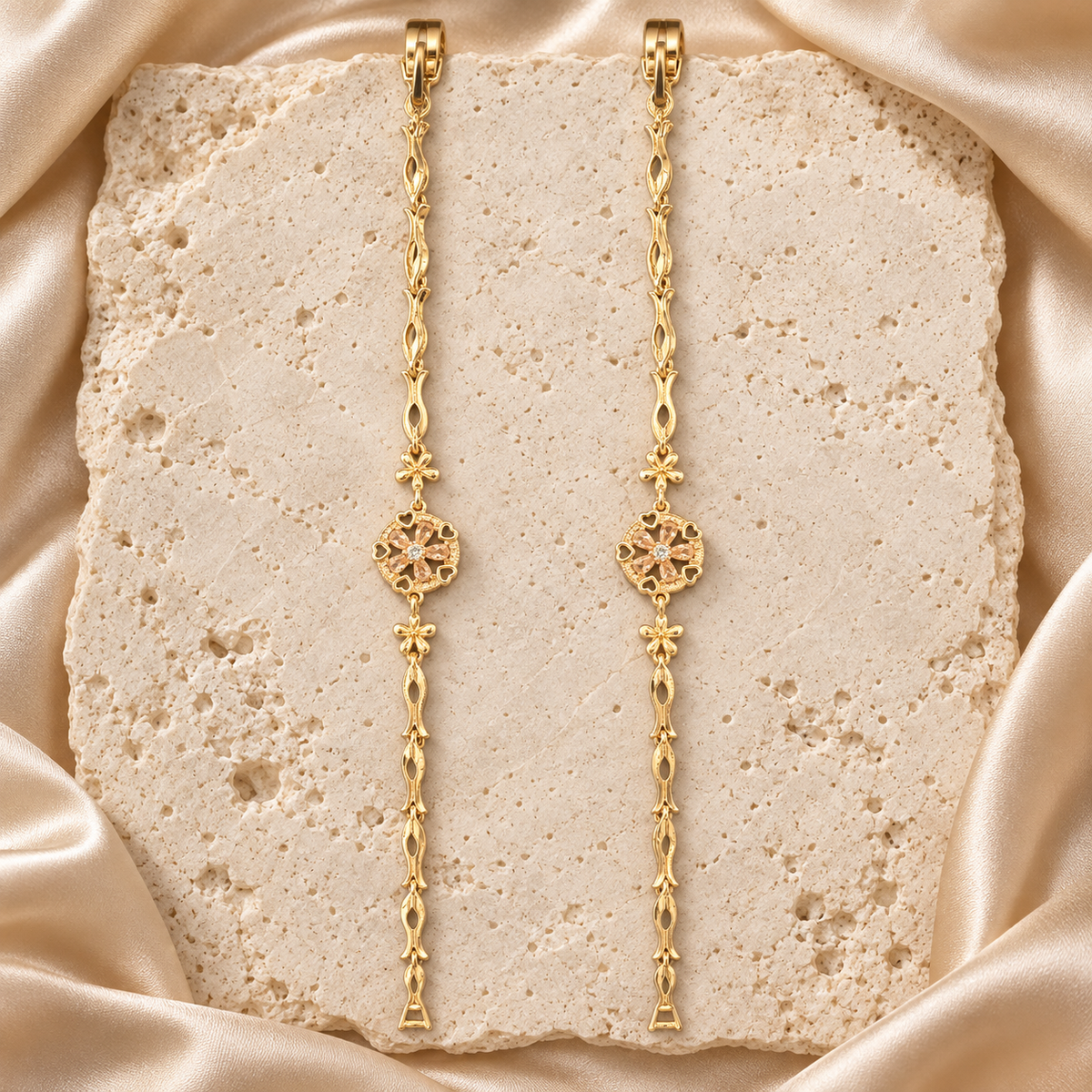 Par de pulseras en tono dorado con medallones florales redondos, corazones calados y eslabones ondulados.
