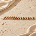 Una pulsera en tono dorado con dieciocho eslabones de serpiente texturizados, detalles rojos y cierre plegable completo.