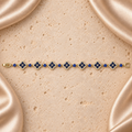 Una pulsera en tono dorado con siete flores de cuatro pétalos, piedras azules, bordes de piedras transparentes y cierre plegable completo.