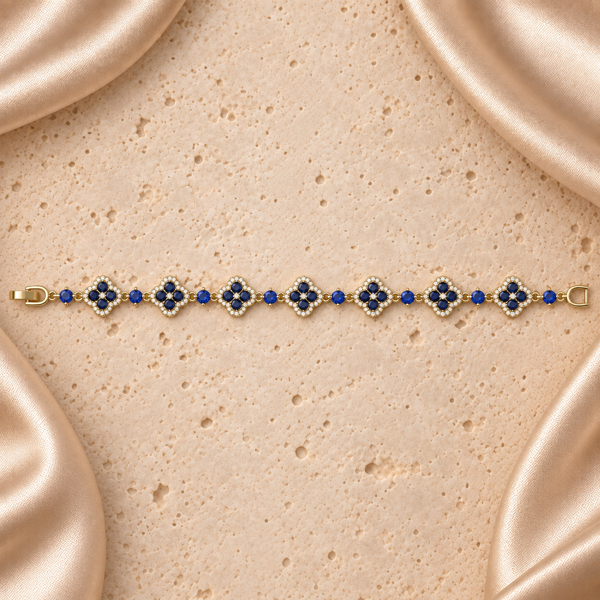 Una pulsera en tono dorado con siete flores de cuatro pétalos, piedras azules, bordes de piedras transparentes y cierre plegable completo.