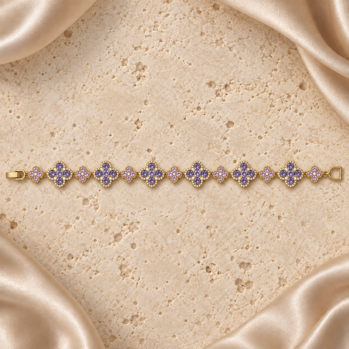 Una pulsera en tono dorado con seis flores grandes y siete pequeñas alternadas, piedras lila, detalles transparentes y cierre completo.