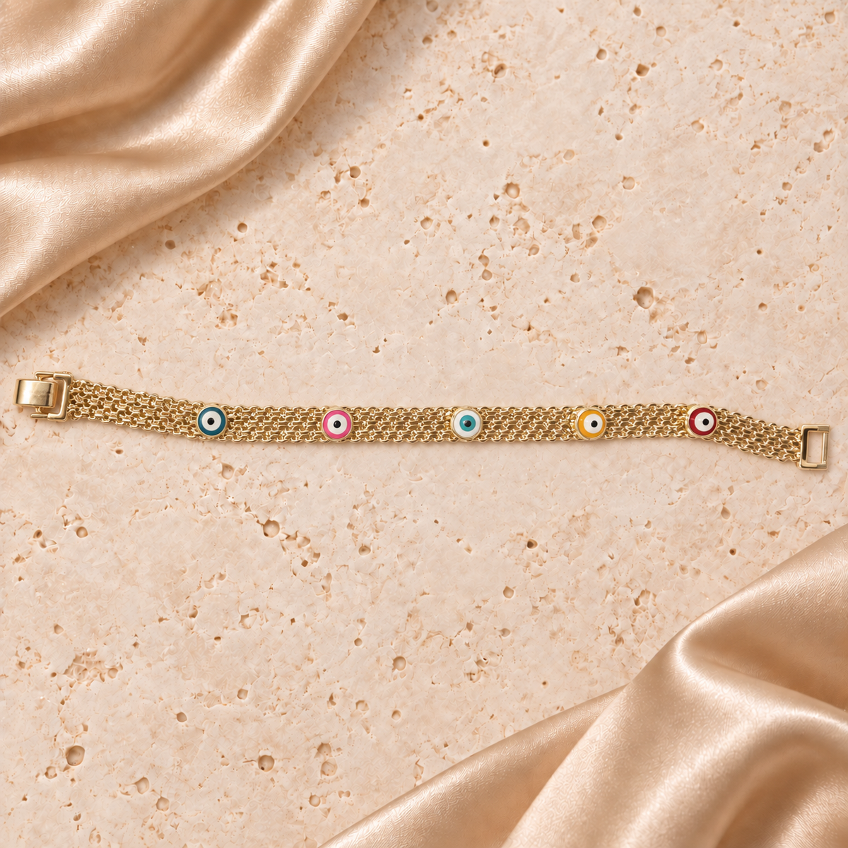 Una pulsera de malla en tono dorado con cinco motivos redondos de ojo en azul, rosa, turquesa, amarillo y rojo, con cierre completo.