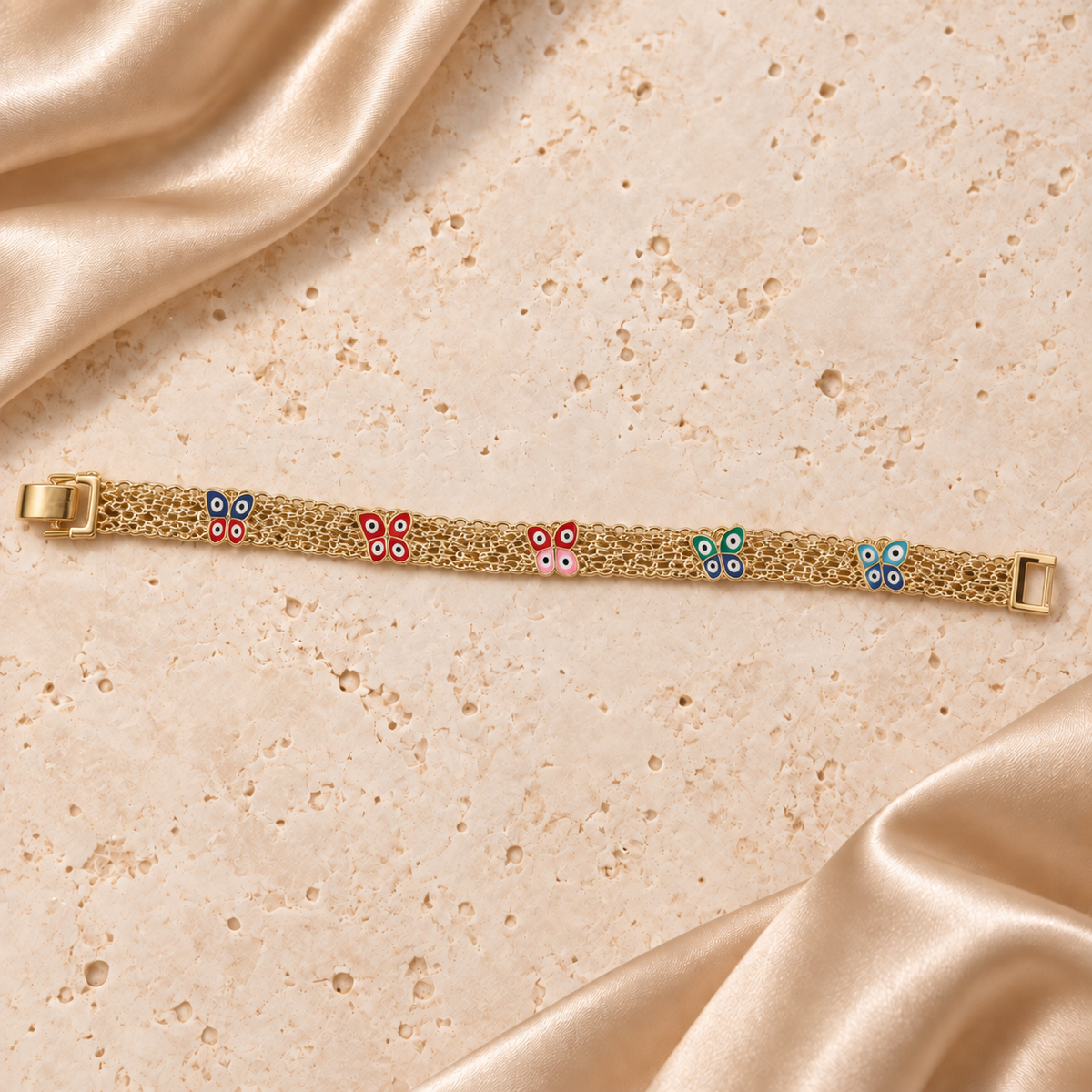 Una pulsera de malla en tono dorado con cinco mariposas multicolor, dibujos de ojos en sus alas y cierre plegable completo.