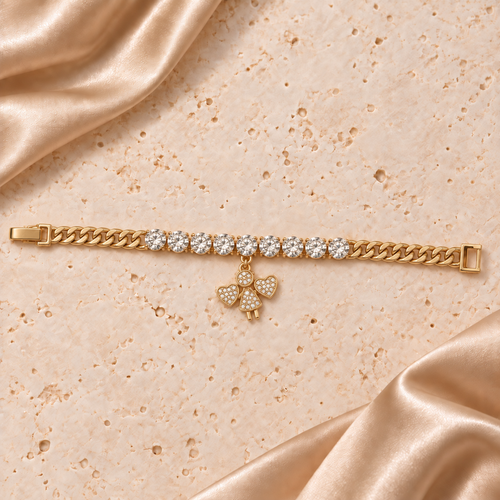 Una pulsera de eslabones en tono dorado con nueve piedras redondas transparentes y un dije de ángel con alas de corazón, con cierre completo.