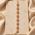 Pulsera en tono dorado con ocho tortugas de caparazón texturizado, bordes de piedras rojas y pequeños eslabones.