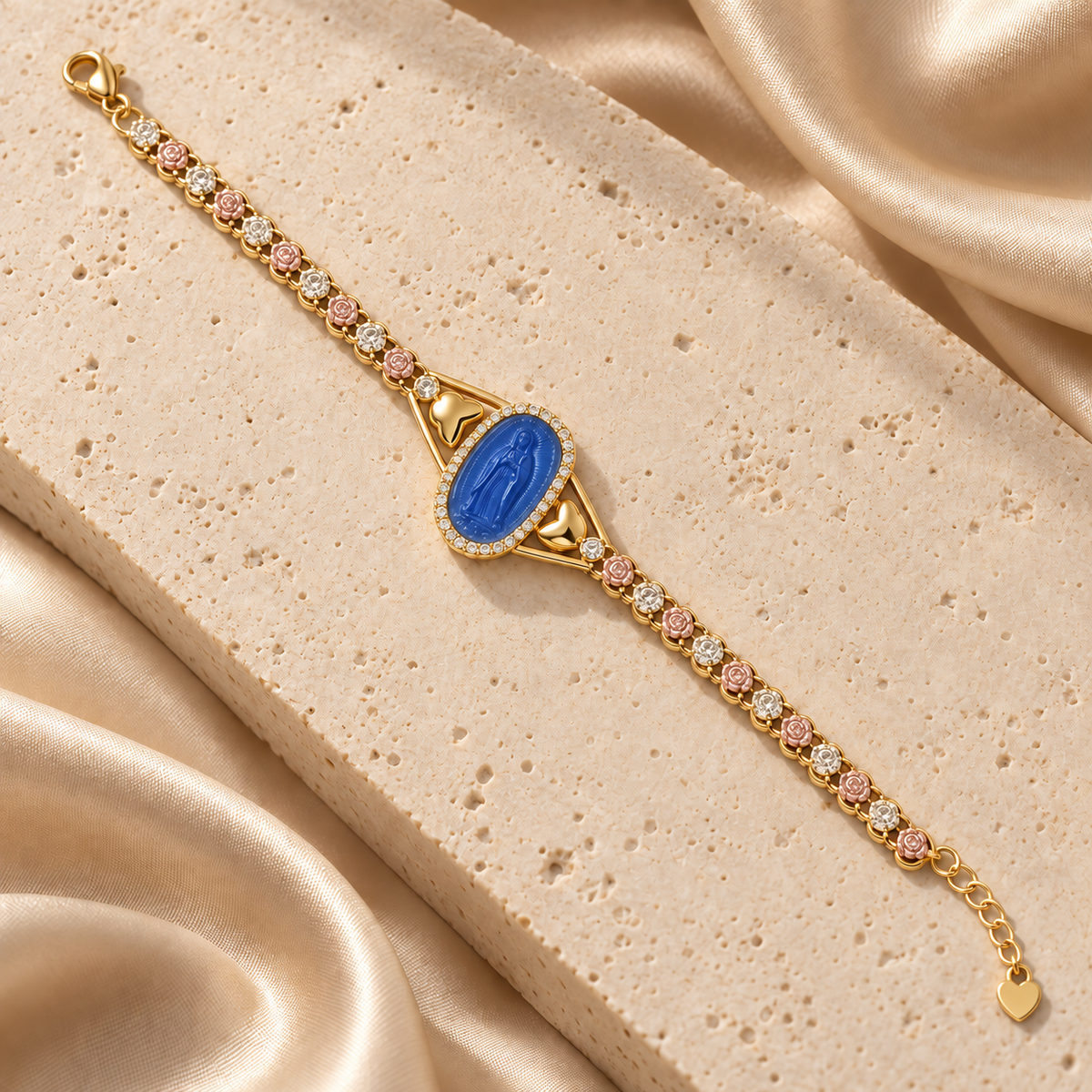 Pulsera con medallón azul de la Virgen de Guadalupe, detalles laterales de corazones, eslabones con rosas y extensión con dije de corazón.
