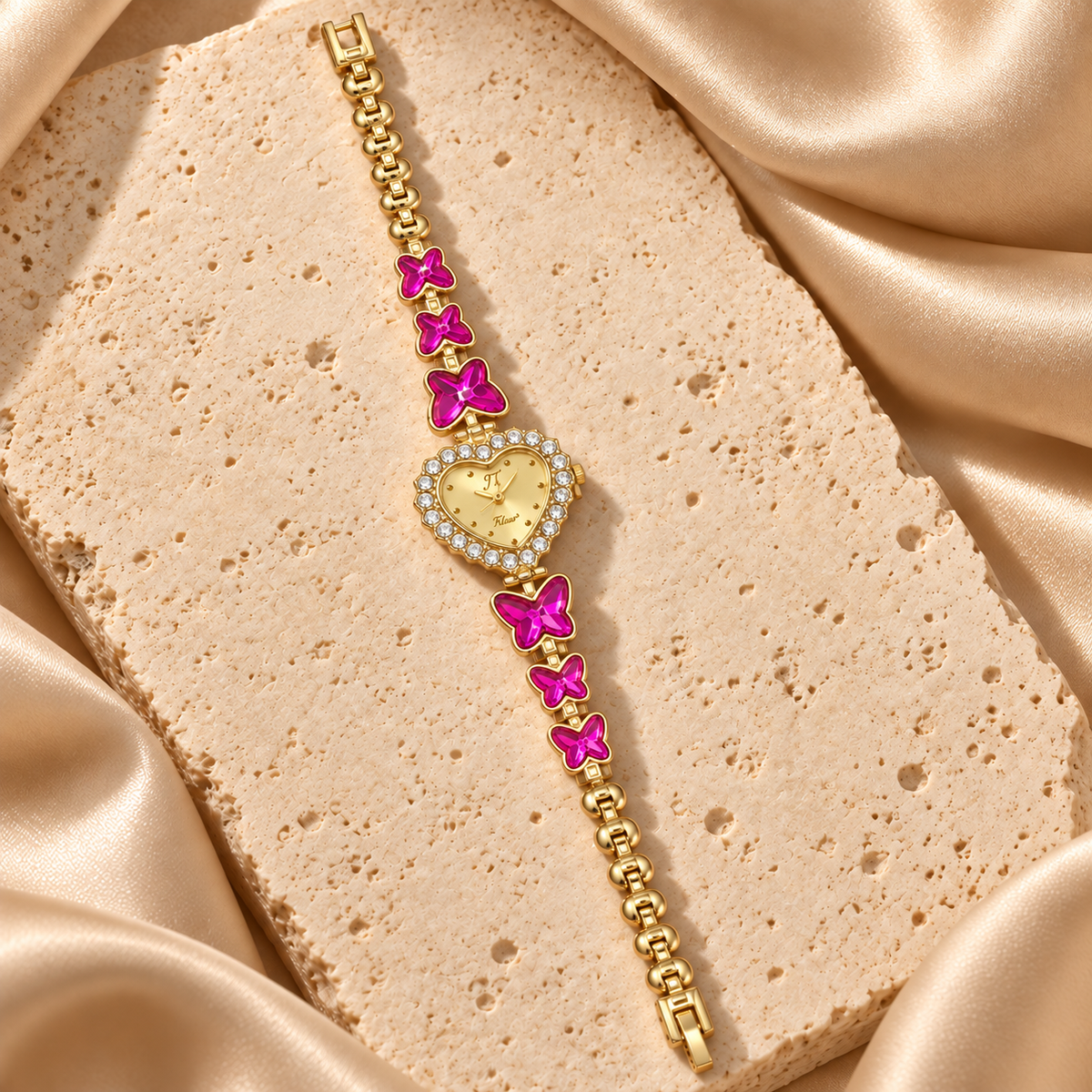 Reloj de pulsera dorado con carátula de corazón rodeada de piedras transparentes y seis mariposas fucsias.