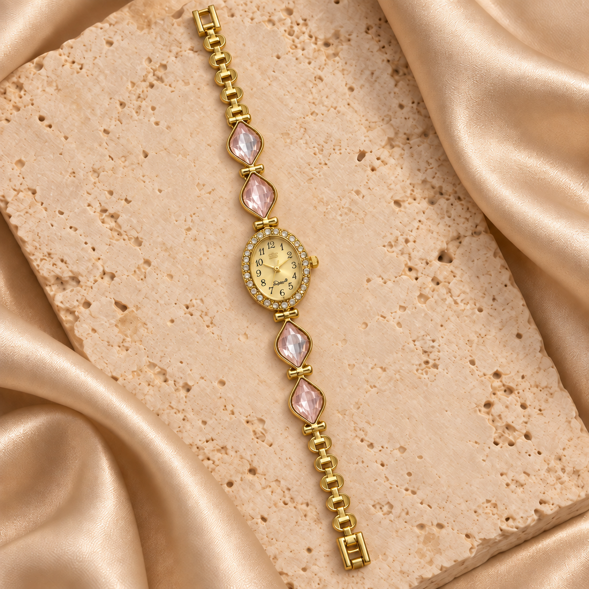 Reloj dorado con carátula ovalada, contorno de piedras transparentes y cuatro hojas facetadas rosas.