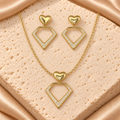 Set dorado de collar y aretes colgantes con corazones pulidos y dijes geométricos abiertos adornados con piedras transparentes.