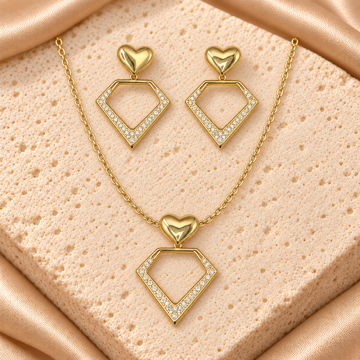 Set dorado de collar y aretes colgantes con corazones pulidos y dijes geométricos abiertos adornados con piedras transparentes.