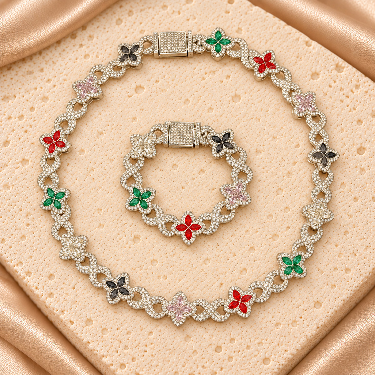 Set de collar y pulsera con flores de cuatro pétalos rojos, verdes, rosas, oscuros y transparentes, unidas por eslabones de infinito brillantes.