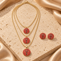 Collar dorado de tres capas con tres dijes redondos de piedras rojas y motivo de llave, acompañado por dos aretes redondos a juego.