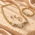 Set dorado de corazones brillantes: collar con tres corazones, pulsera, dos aretes de broche y un anillo sobre piedra crema y satén.